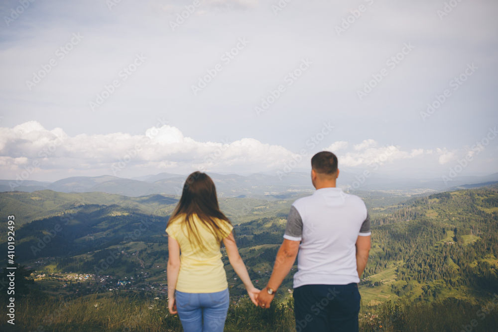 Amazing view of young adorable couple embracing, kissing each other in the green dense mountain region. Summertime, sunset. Couple goals. Forever in love. Love story.