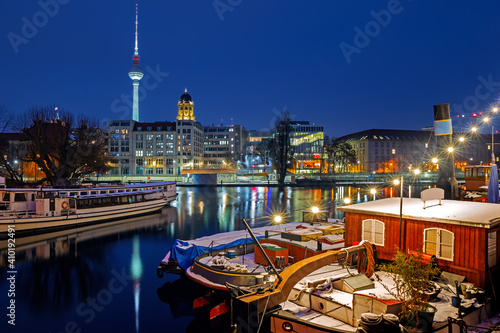 Illuminated Berlin at winter night against the Spree river, historical harbor in the downtown with old boats 