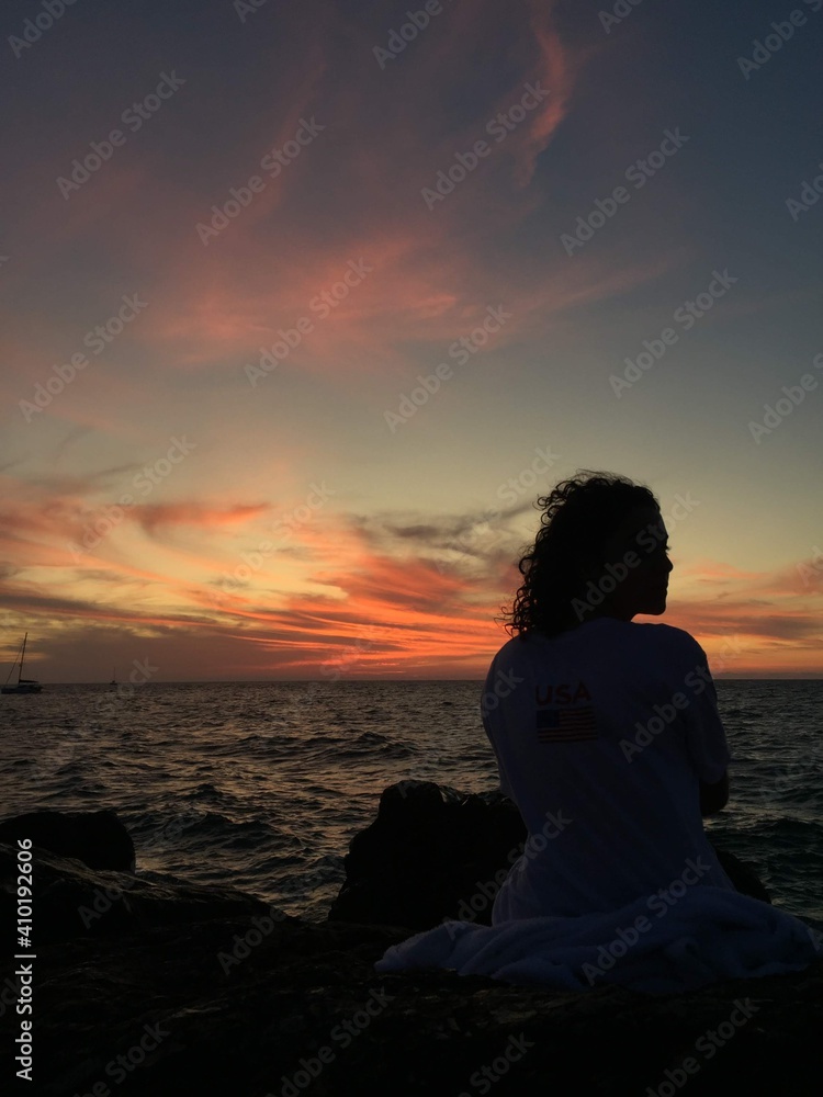 a girl watching the sun at the ocean