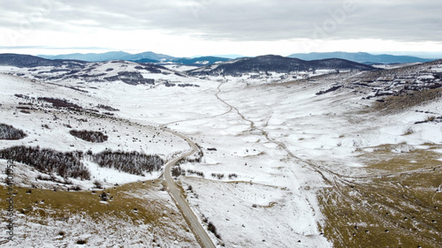 Aerial drone view of road in idyllic winter landscape. Snowy road on mountain.