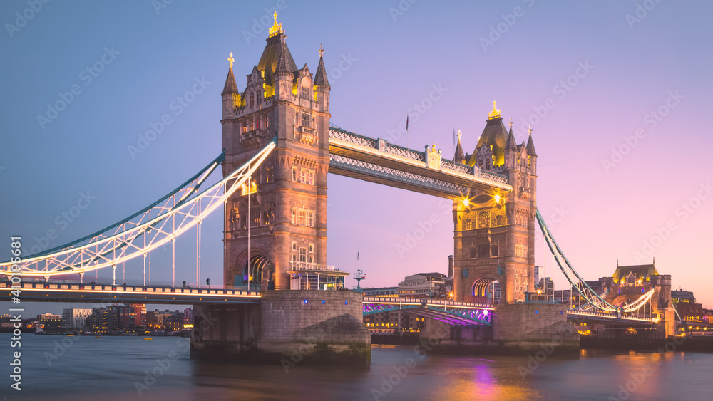 Obraz premium The lights of the iconic Tower Bridge come on at sunset over the Thames in London, England