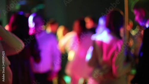 Blurred silhouettes of people dancing at a party in a nightclub. Soft focus, slow motion. Party with neon laser lights. Have fun tonight. Dance event
