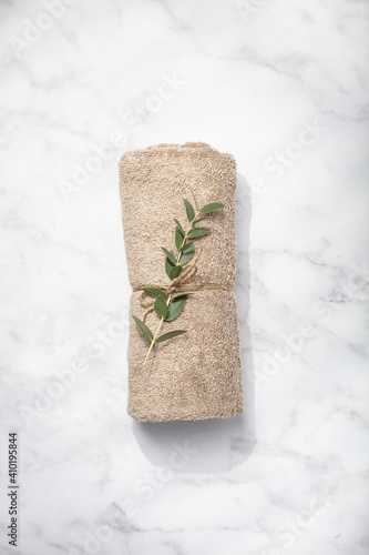 Green branch and SPA towel on white marble background