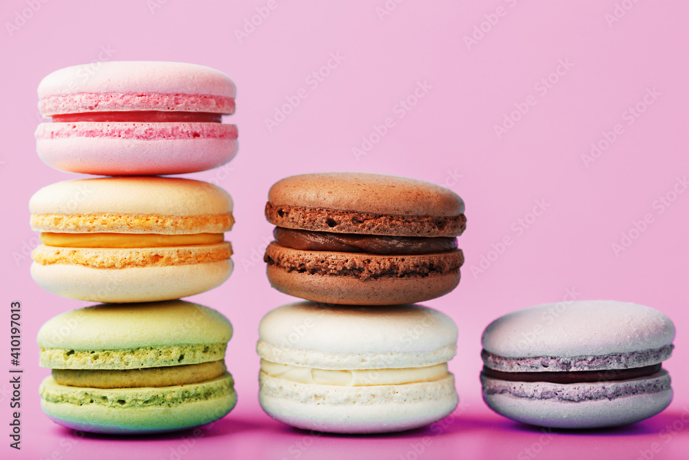 Colorful French macaroni cookies are arranged in a pyramid on the background. Colorful French macaroni cookies are arranged in a pyramid on the background.