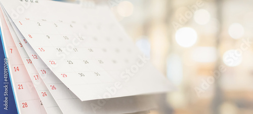 Close up white paper desk calendar with blurred bokeh background appointment and business meeting concept photo