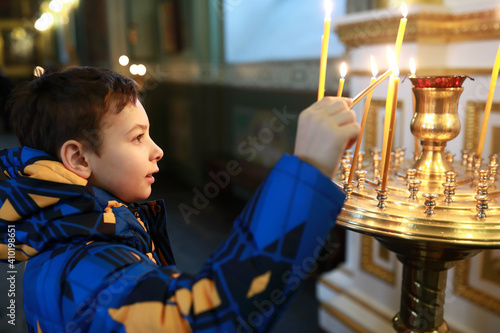 Obraz na plátně Child with lit candle in cathedral