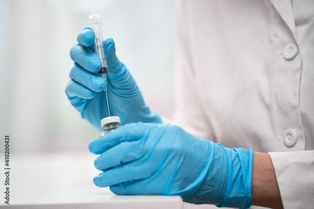 Doctor dials the vaccine into a syringe Doctor dials the vaccine into a syringe