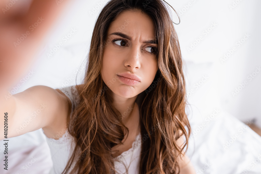 Pensive woman in pajama looking away in bedroom on blurred background Pensive woman in pajama looking away in bedroom on blurred background