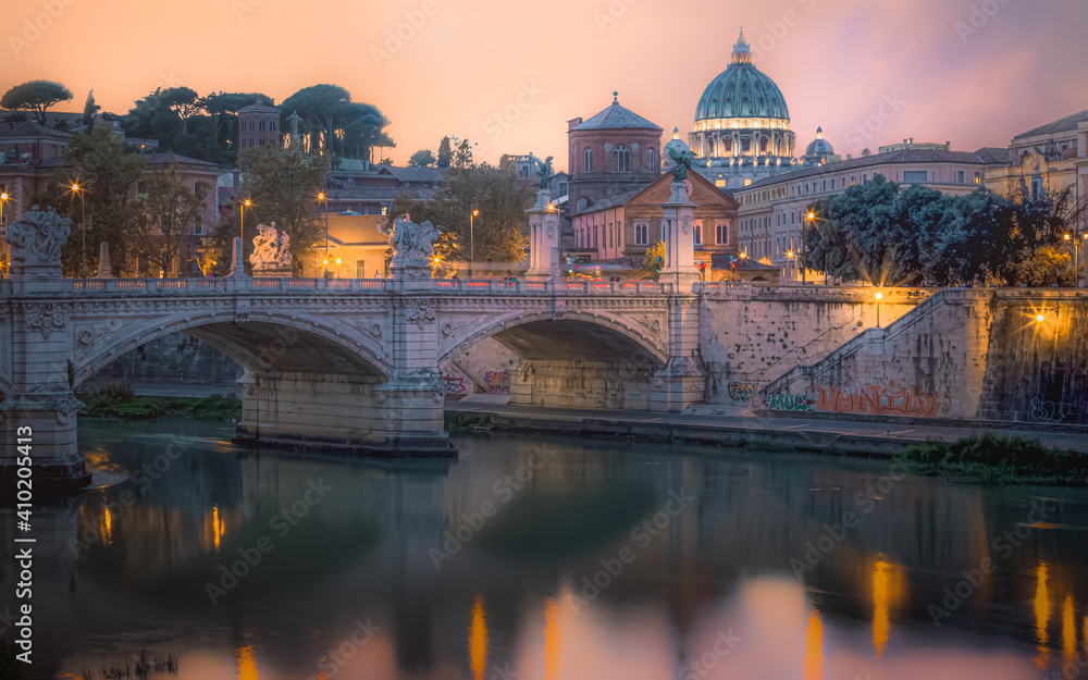 A colourful sunset view of Ponte Vittorio Emanuele II, St. Peter's Basilica and Vatican City over the Tiber River in Rome, Italy.