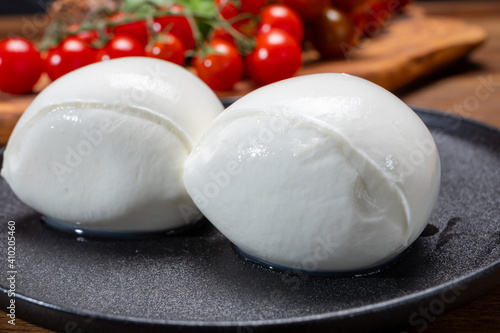 Cheese collection, white balls of soft Italian cheese mozzarella, served with red cherry tomatoes, fresh basil leaves