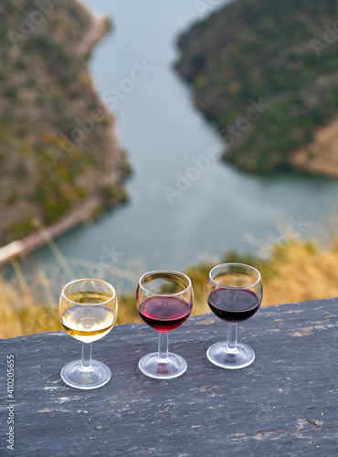 Tasting of Portuguese fortified port wine, produced in Douro Valley with Douro river and colorful terraced vineyards on background in autumn, Portugal