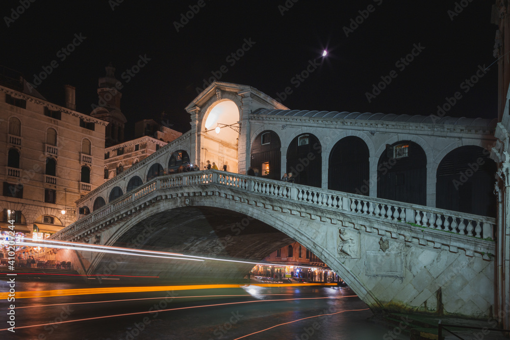 A vaporetto water bus leaves a trail of light at night as under the famous Rialto Bridge in Venice, Italy. A vaporetto water bus leaves a trail of light at night as under the famous Rialto Bridge in Venice, Italy.
