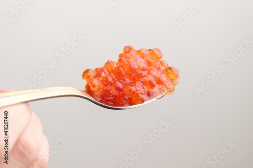 Salmon red caviar in a golden spoon on the white background with copy space. 