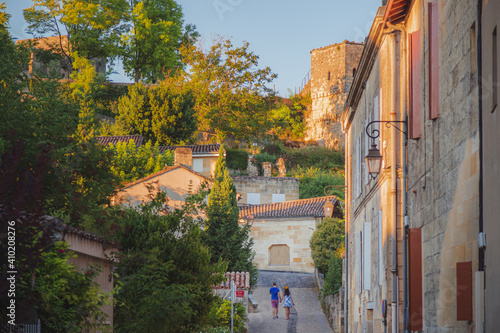 A tourist couple hold hands strolling through the charming French wine country old town village of Saint Emilion in Bordeaux, France.