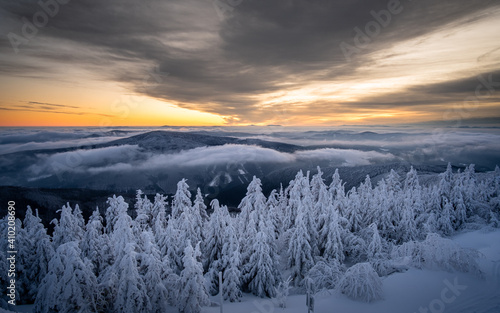 Beautiful Winter sunrise above the clouds. Trees covered in snow. Mist in a valley. Lysa Hora in winter Czech Republic. 