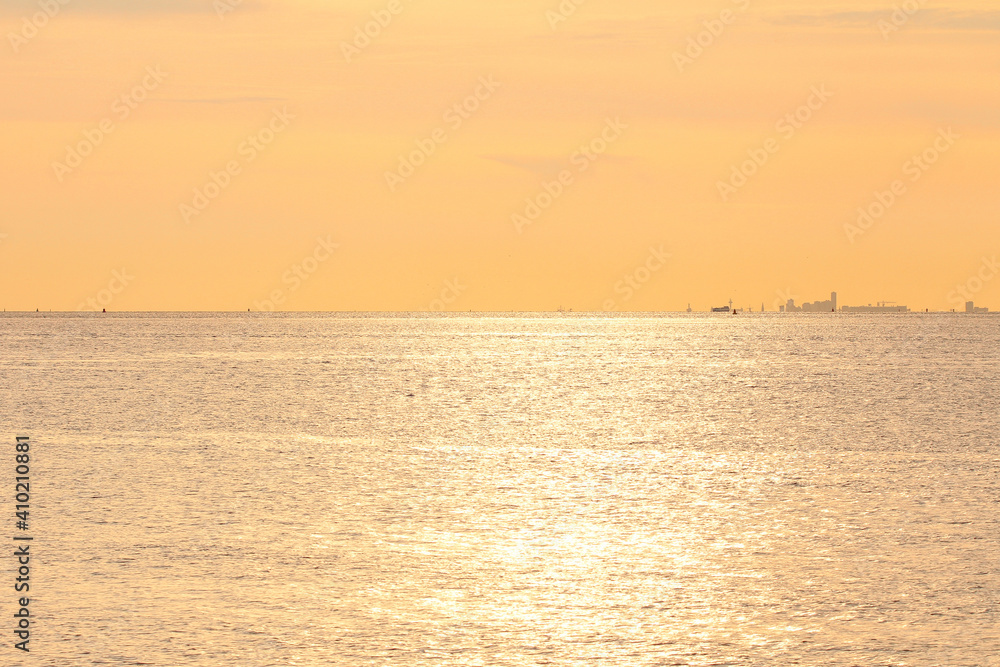 beautiful seascape with a soft orange sky above the sea water at the coast  in zeeland, the netherlands at the westerschelde sea at a summer evening