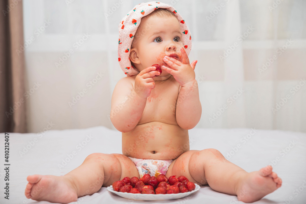 cute stained baby in a hat eating berries in bed cute stained baby in a hat eating berries in bed