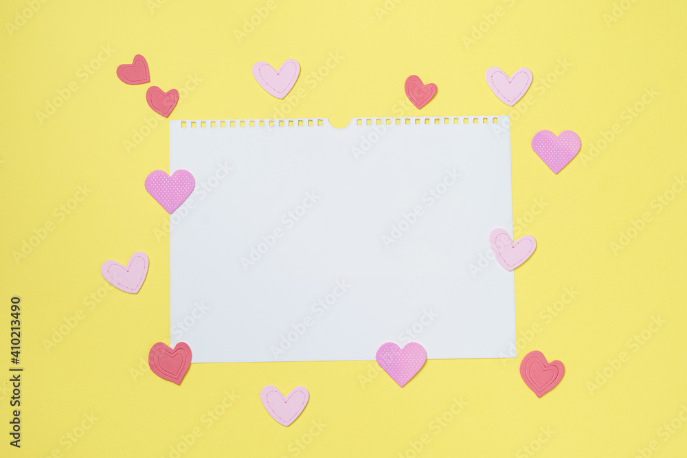 Elements in shape of hearts on yellow background surrounding white paper. Symbols of love for Happy Women's, Mother's, Valentine's Day, birthday greeting card design.