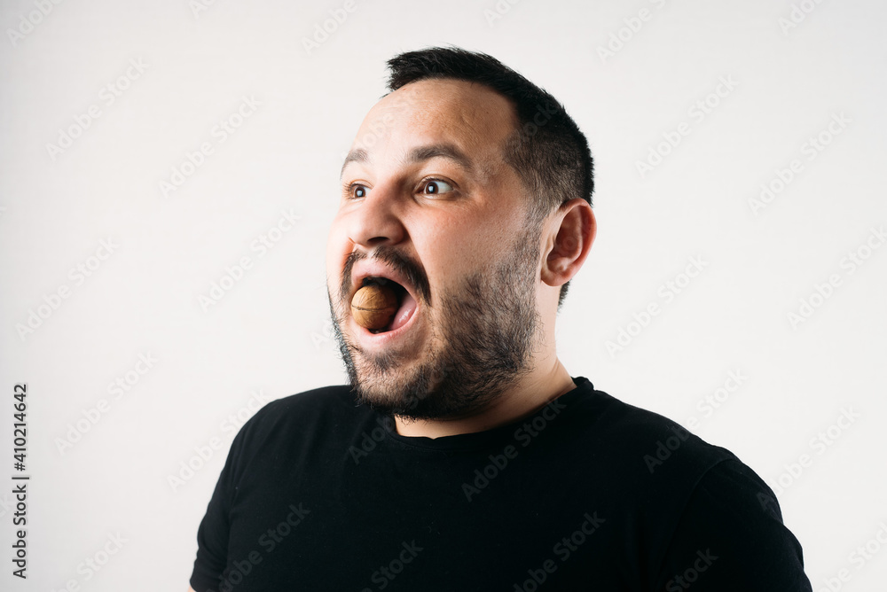 a man tries to crack a nut with his teeth. the concept of a complex problem or strong teeth a man tries to crack a nut with his teeth. the concept of a complex problem or strong teeth