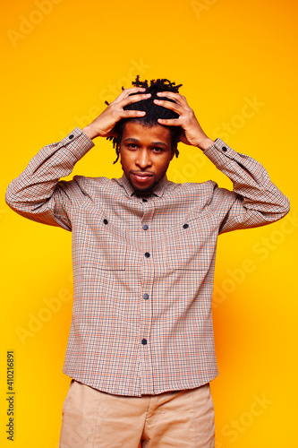 young handsome african american guy student posing cheerful and gesturing on yellow background, lifestyle people concept © iordani