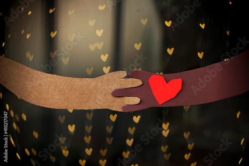 Holding hands between a couple with different skin color on a beautiful hearted background photo