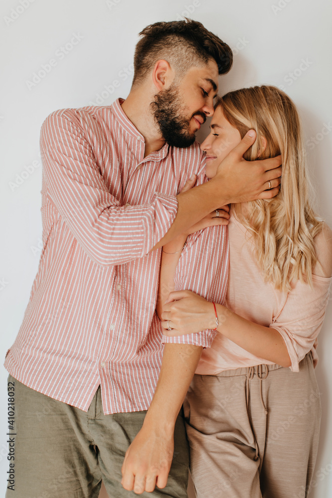 Romantic couple in bright summer clothes with smile posing on white background. Guy and girl hug and enjoy good mood Romantic couple in bright summer clothes with smile posing on white background. Guy and girl hug and enjoy good mood