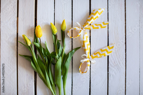 Yellow tulips with decotarive napkins shaped as easter bunny on white wooden background. Creative idea and concept. Flat lay. photo