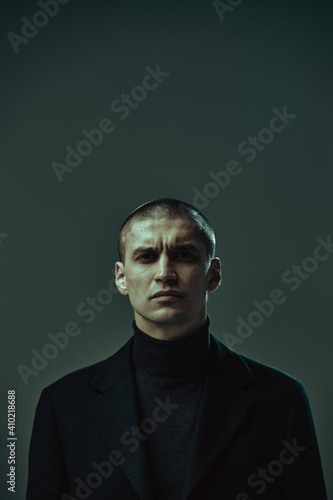 Foto Portrait of serious masculine frowning businessman in black suit on gray studio background