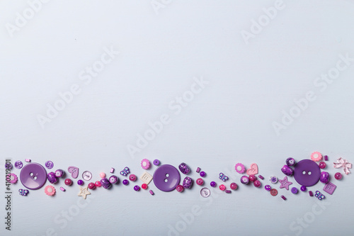 Beads and buttons for sewing and embroidery. Purple set of materials for handcraft, making of bijouterie and accessories. White background, copy space.