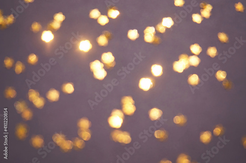 Gold bokeh stars on purple background. Yellow glitter backdrop. Golden texture. New year luxury snow. Copyspace. Shimmer confetti wallpaper. Dreamy shiny design detail