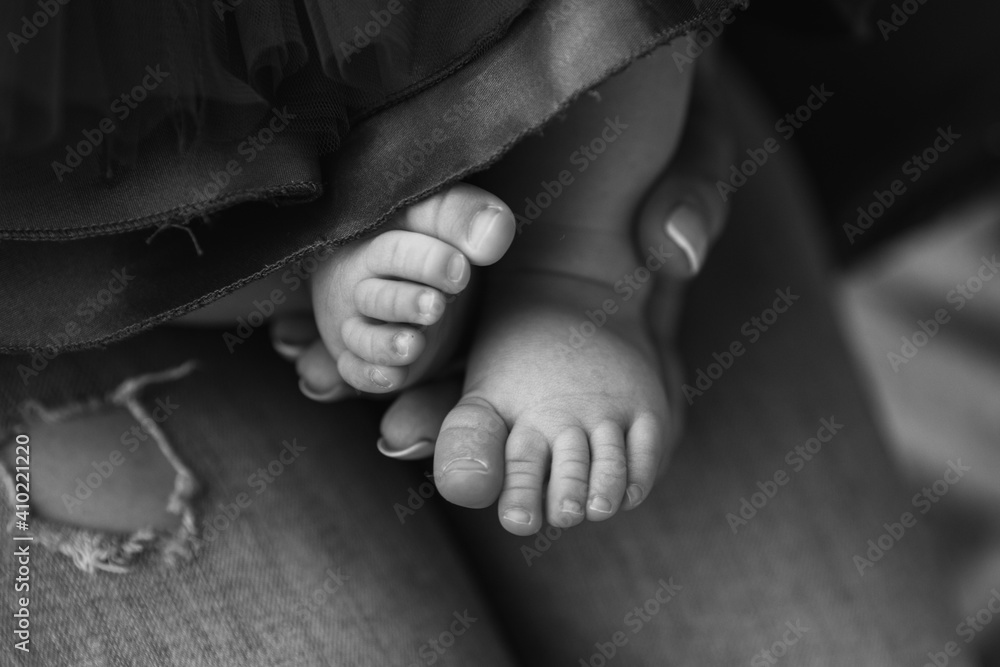 Tiny baby feet of the firstborn in the loving arms of a young mother Tiny baby feet of the firstborn in the loving arms of a young mother