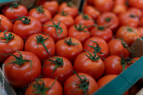 Soft focused shot of vegetable department in grocery store, supermarket, mall, hypermarket or shopping center. Boxes with tomatoes. Vegan healthy food concept.