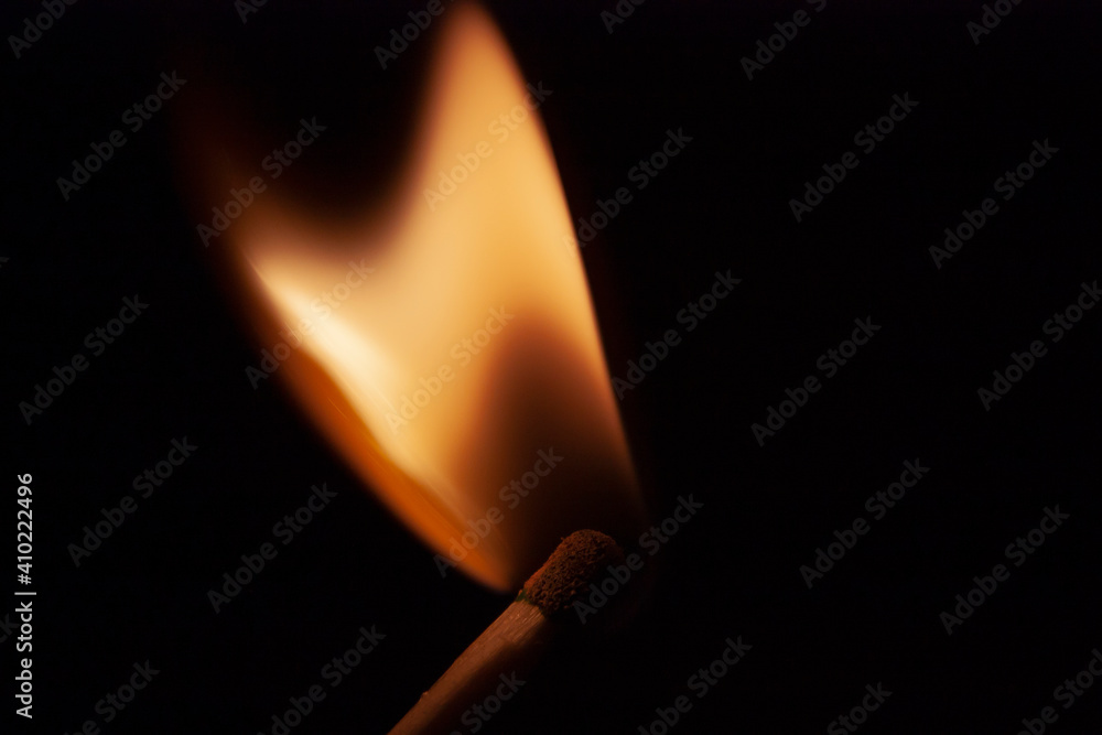 Horizontal close-up conceptual photography of a single wooden burning with bright orange hot flame match on the darkness Horizontal close-up conceptual photography of a single wooden burning with bright orange hot flame match on the darkness