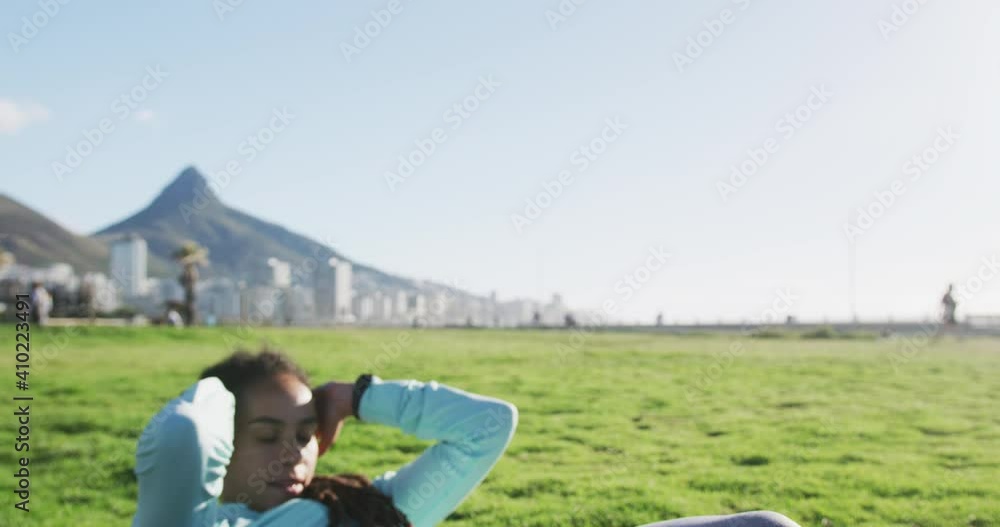 African american woman in sportswear doing sit ups in park African american woman in sportswear doing sit ups in park