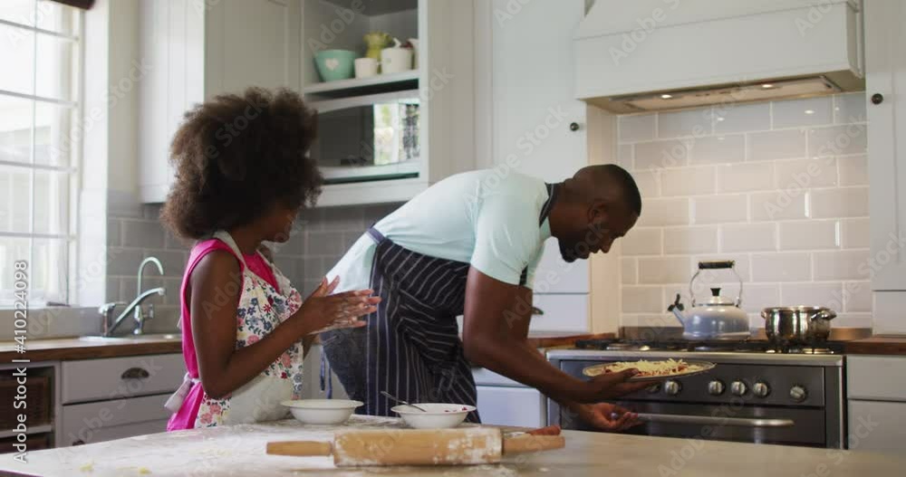 African american daughter and her father making pizza together in kitchen African american daughter and her father making pizza together in kitchen