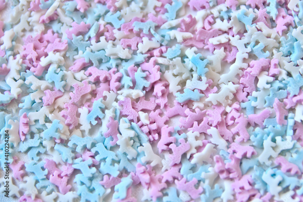 Delicious sugar candy unicorns in red, blue and white as sweet cake decoration and birthday topping with little horses and unicorn sprinkles as delicious background for confection frosting of donuts Delicious sugar candy unicorns in red, blue and white as sweet cake decoration and birthday topping with little horses and unicorn sprinkles as delicious background for confection frosting of donuts