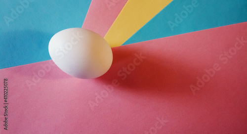 Easter concept. White egg on a multicolored background in pastel colors. The chicken laid the egg. Natural organic homemade products. Happy Easter card with copy space for text.