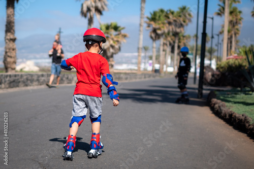 Back view of little boy practicing with roller-skates