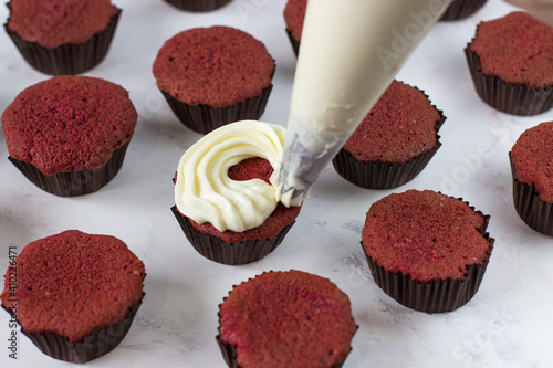 The process of applying the cream on a cupcake red velvet