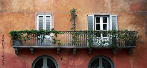 Obraz na płótnie Retro, italian style orange wall with window shutters and a balcony. Romantic postcard view from small town in Italy. w salonie