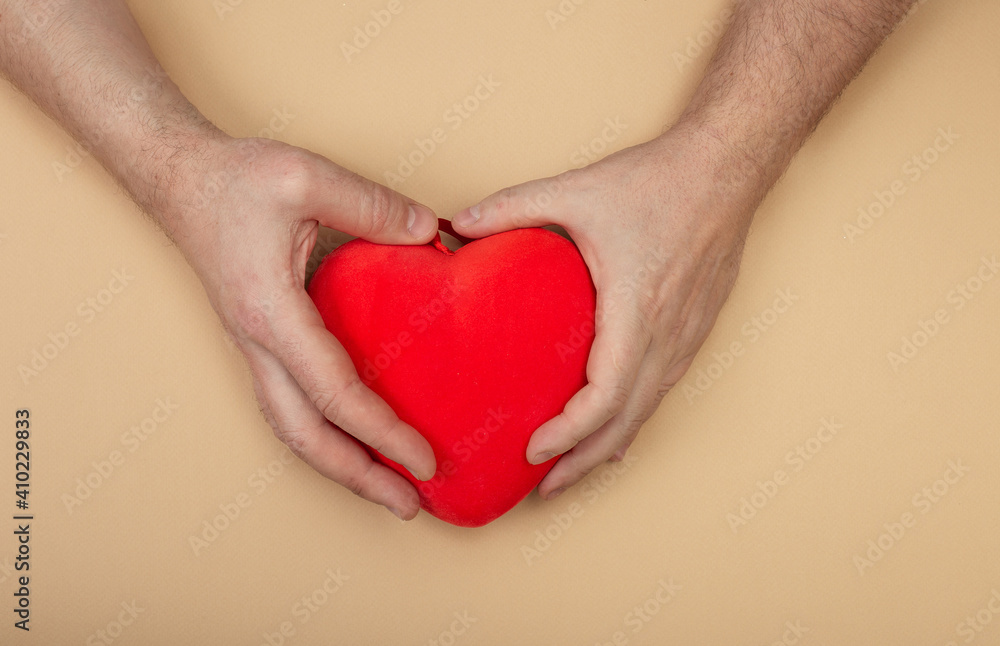 LGBT concept with men hands holding red heart on beige background. Hands of homosexual couple on set sail champagne color. Same sex love. Gay Valentines card LGBT concept with men hands holding red heart on beige background. Hands of homosexual couple on set sail champagne color. Same sex love. Gay Valentines card