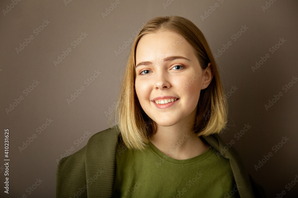Young smiling attractive woman on dark gray background. Happy Caucasian Teenager Girl Blond hair Portrait with copy space Young smiling attractive woman on dark gray background. Happy Caucasian Teenager Girl Blond hair Portrait with copy space