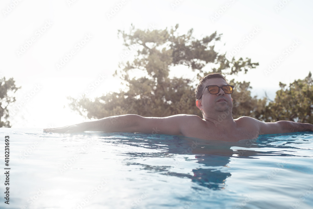 Man relaxing in the swimmind pool against the sea and nature