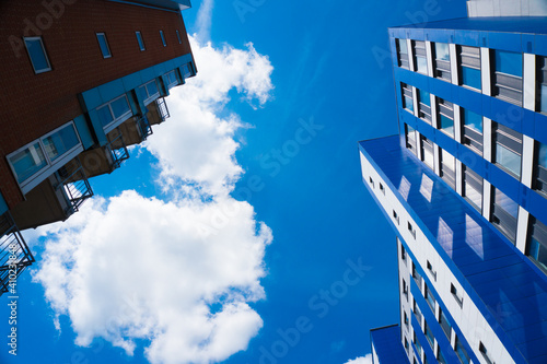 White bright clouds on top of high rise buildings and blue sky.