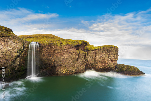 Coastal cliff waterfall into the ocean long exposure