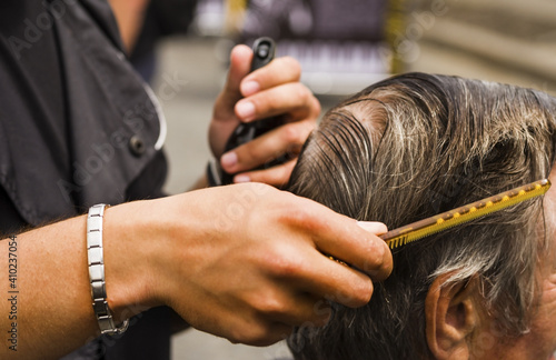 The hairdresser cuts and combs the man. Barber's hands with scissors and a hairbrush