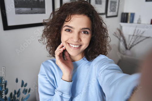 Принти на полотні Happy pretty hispanic gen z teen girl holding smartphone looking at camera taking selfie shot for social media, making video call at home by virtual mobile app