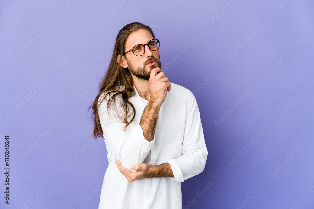 Young man with long hair look looking sideways with doubtful and skeptical expression. Young man with long hair look looking sideways with doubtful and skeptical expression.