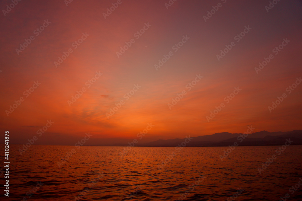 Sunrise from Catamaran Yacht over the sea with mountains in the background in Sicily. Low light photo of sunrise over the Mediterranean sea. 