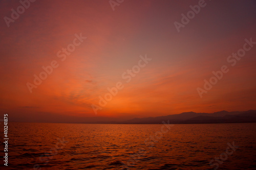 Sunrise from Catamaran Yacht over the sea with mountains in the background in Sicily. Low light photo of sunrise over the Mediterranean sea. 